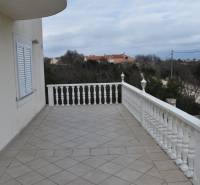 The terrace of a family house in Pridraga with white railings and lights, overlooking the landscape.