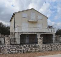 A family house in Pridraga with a stone facade and a balcony, surrounded by a stone fence.