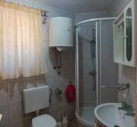 A bathroom with ceramic tiles, a shower enclosure, and a sink in a family house.