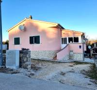 A family house in Pridraga with a pink facade and stone details on the driveway.