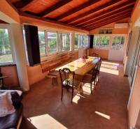 A glazed terrace in a family house with a wooden ceiling and a large table.