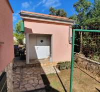 A family house in Pridraga with a stone path, garden, and white doors.