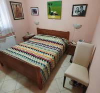 A bedroom in a family house with a colorful bedspread, decorations, and a radiator.