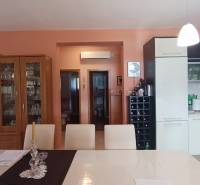 Interior of a family house with a kitchen, dining table, and a cabinet with glassware.