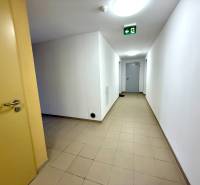 A corridor with white walls and tiles in an apartment building.