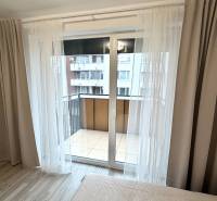 In the 1-room apartment, there are glazed doors leading to a balcony with a wooden decor floor.