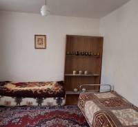 A room in a family house with two beds, a carpet, and a shelf on the wall.
