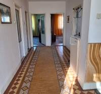 A hallway in a family house with a carpet and tiles with a geometric pattern.
