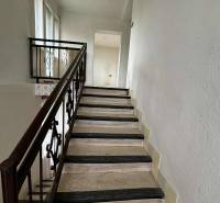 The staircase in the family house with a metal railing and windows provides natural light.