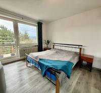 A bedroom in a family house with a wooden decor floor and large windows.