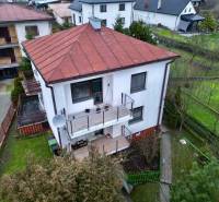 A family house in Nesluša with a sloped roof, a terrace, and a view of the surrounding houses.