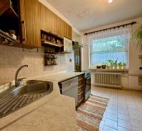 A kitchen in a family house with a view of the garden, light tiles, wooden cabinet decor.