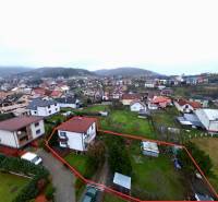 Aerial view of a family house in Nesluša, surrounded by a garden and surrounding buildings.