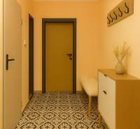 A hallway in a 3-room apartment with a patterned floor and a coat rack on the wall.
