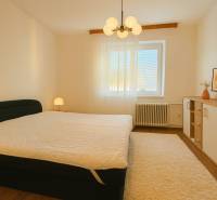 Bedroom in a 3-room apartment with a bed, lamp, and carpet flooring with a wooden decor.