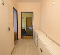 A hallway in a 3-room apartment with a wooden decor floor and white furniture.