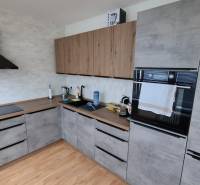 A kitchen in a 3-room apartment with a wooden decor floor and modern appliances.
