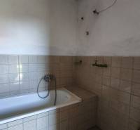 A bathroom in a family house with a bathtub tiled with light tiles.