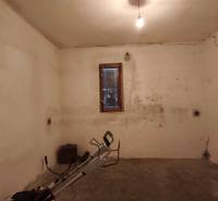 Basement with a window in a family house, walls with cracks and simple lighting.