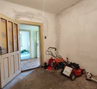 Interior of a family house with open doors, a lawnmower, and tools on the floor.