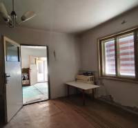 The interior of a room in a family house with open doors and a table by the window.