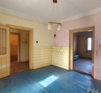 A room with a blue floor with a wooden decor, old doors, and cracks in the wall.