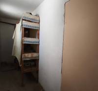 A narrow hallway with shelves in a family house, simple furnishings.