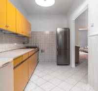 A kitchen in a 3-room apartment with tiles, yellow cabinets, and a stainless steel refrigerator.