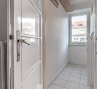 A narrow room with a window, tiled floor, and a white radiator in a 3-room apartment.