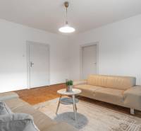Living room in a three-room apartment with light sofas and a wooden decor floor.