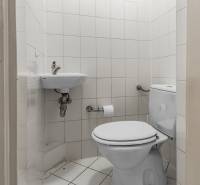 A toilet with white tiles in a 3-room apartment, a small sink area, and a toilet.