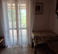 A room in a family house with a window, a curtain, and a table with a tablecloth.