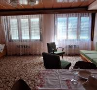 Living room in a family house with a sofa, armchairs, a wardrobe, and covered windows.
