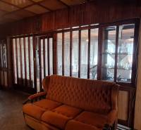 Interior with a brown sofa, glass doors, and a display cabinet in a family house.