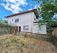 A family house in Nová Bašta with a garden and a partially cloudy sky.