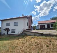A family house in Nová Bašta with a grassy plot and an annex under the blue sky.