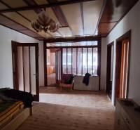 Interior of a family house with a wood-patterned floor, wooden doors, and older furniture.