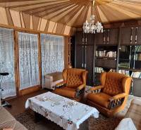 Living room with a library, orange armchairs, and a chandelier in a family house.