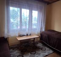 A room in a family house with two beds, a coffee table, and curtains.
