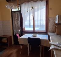 A kitchen in a family house with a wooden decor floor, a stove, and a table by the window.