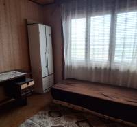A room in a family house with a bed, table, and wardrobe, featuring a wooden floor decor.