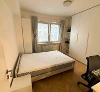 Bedroom in a 4-room apartment with a bed, wardrobe, and wooden decor flooring.