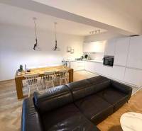 Living room with kitchen in a 4-room apartment, wooden decor flooring, spacious sofa and dining table.