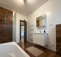 Bathroom with a shower, bathtub, and sanitary ware, floor with wooden decor in a family house.