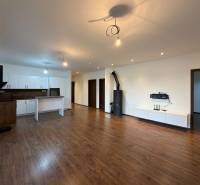 Open living room with kitchen in a family house, wooden decor flooring, white furniture.