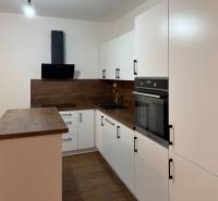 A kitchen in a family house with white cabinets and a wood-patterned floor.