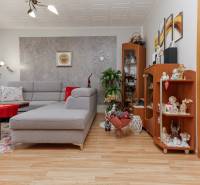 Living room in a three-room apartment with a sofa and shelves, floor with wood decor.
