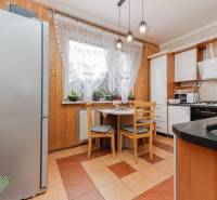 A kitchen in a 3-room apartment with a wooden decor, equipped with a cooktop and a refrigerator.