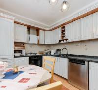 A kitchen in a 3-room apartment with white cabinets and a dining table with decoration.