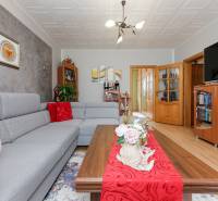 Living room in a 3-room apartment with a gray sofa, wooden decor flooring, and decorations.